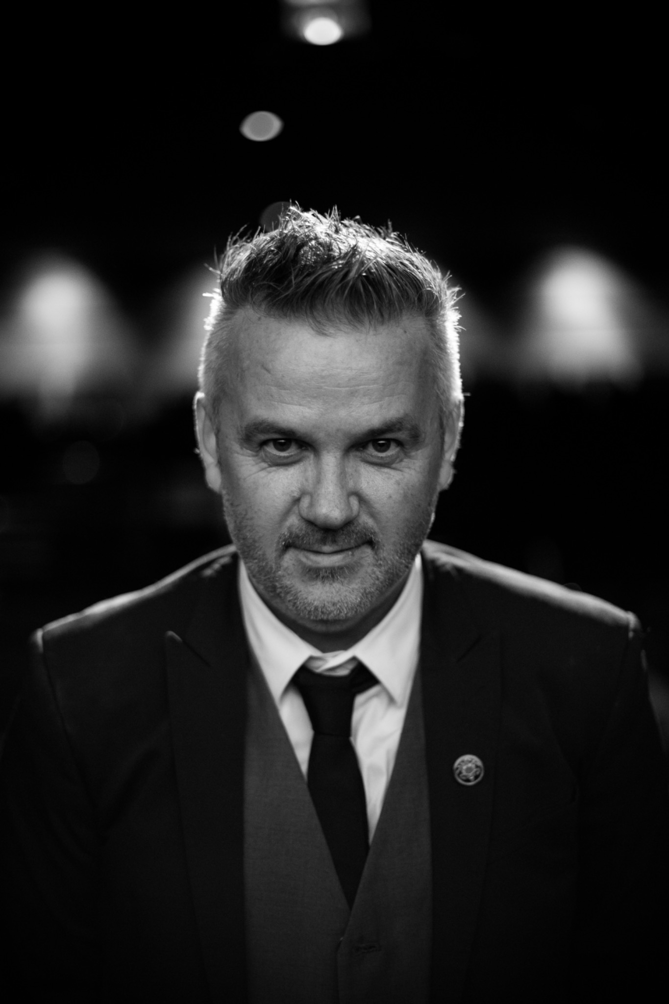 A formal portrait of a man against a dark background
