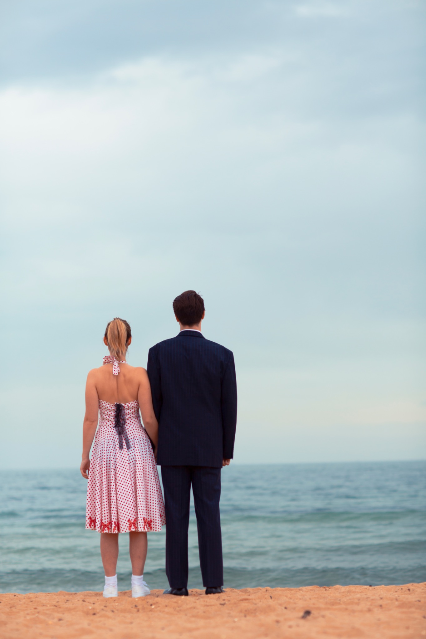 A couple on a beach looking toward the sea